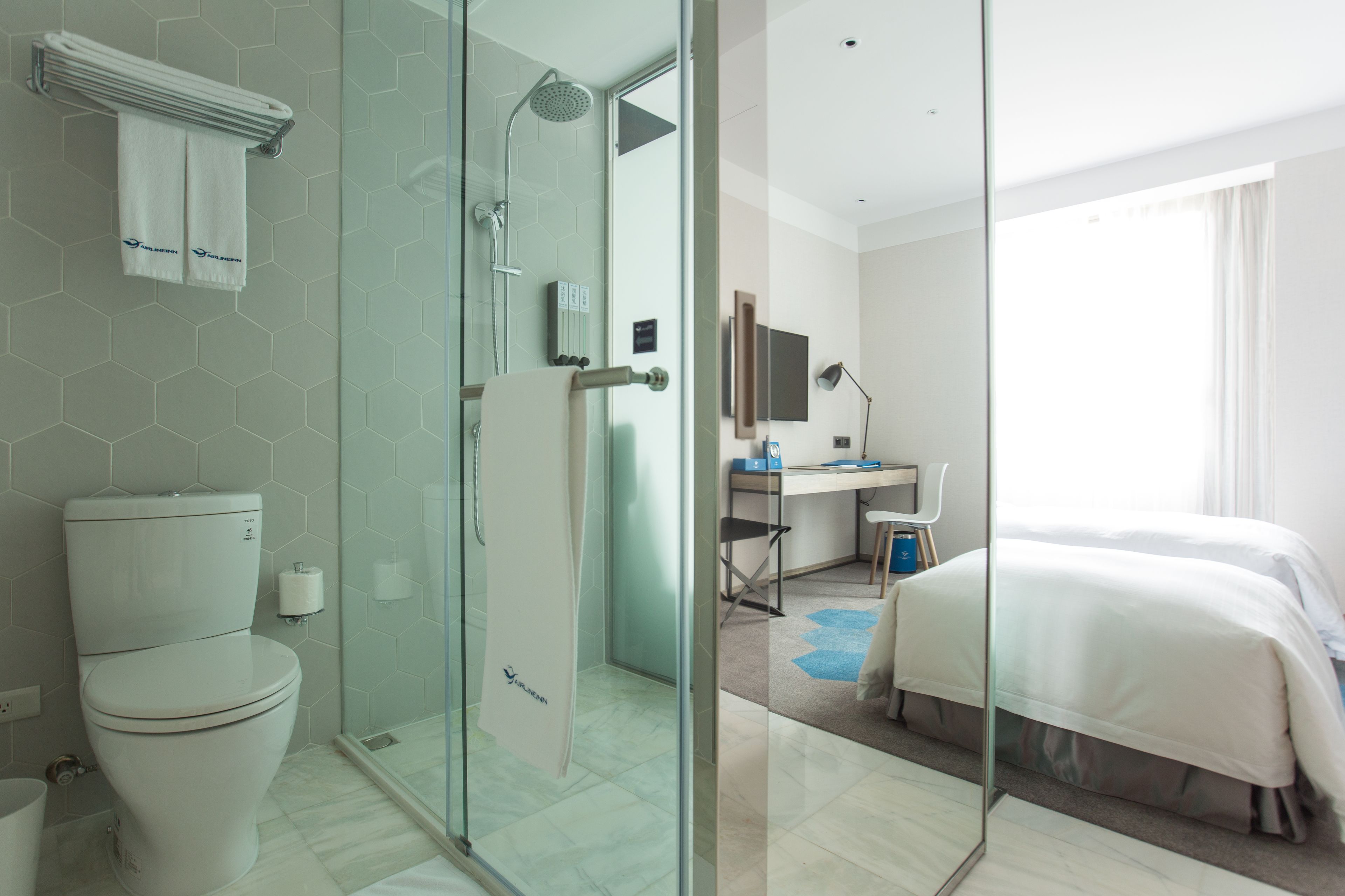 A modern hotel bathroom with a glass shower enclosure, a toilet, and a sink.