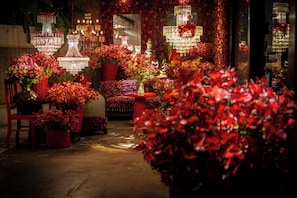 Un espace intérieur bien éclairé, agrémenté de plusieurs lustres, de fleurs rouges et de meubles en osier.