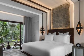 Una habitación de hotel moderna con una cama grande, vistas a un jardín y una pared de piedra.