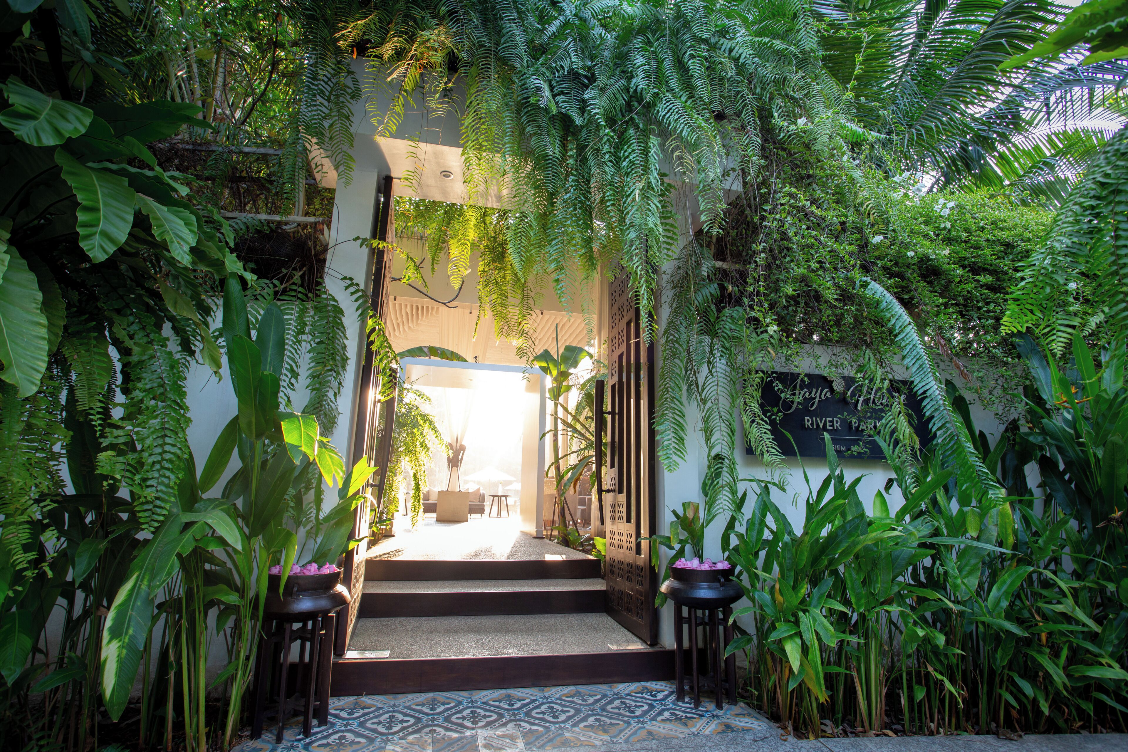 Un rigoglioso giardino interno che conduce a una zona salotto con vista sull'esterno.