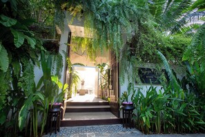 Un jardin intérieur luxuriant qui mène à un espace de détente offrant une vue sur l’extérieur.