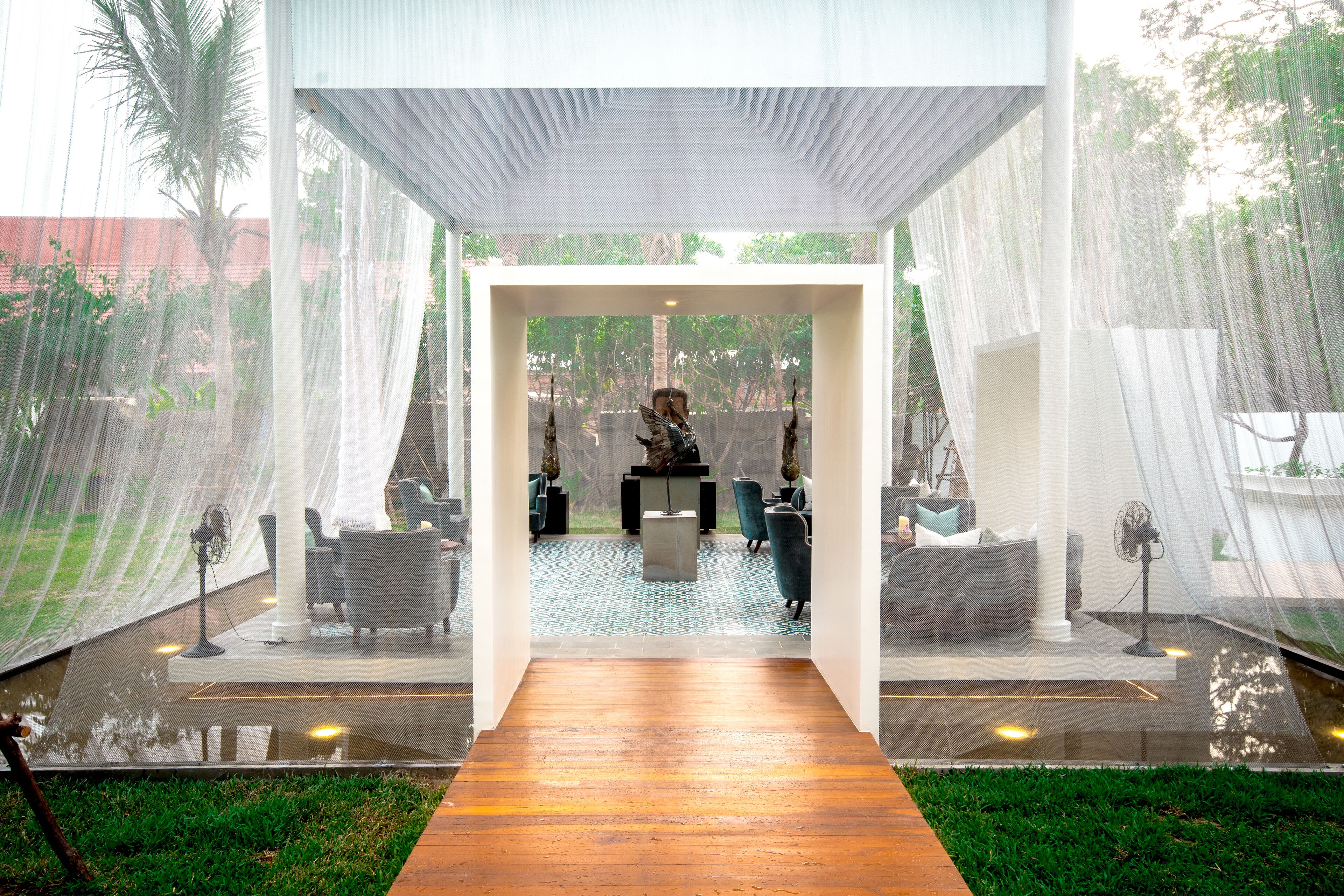 A modern indoor space with a wooden floor leading to a seating area with chairs and a table.