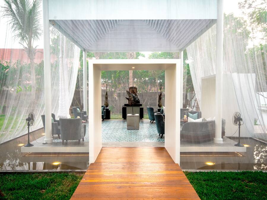 A modern indoor space with a wooden floor leading to a seating area with chairs and a table.