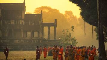 A group of monks in traditional orange robes walking towards a temple complex with ancient architecture.