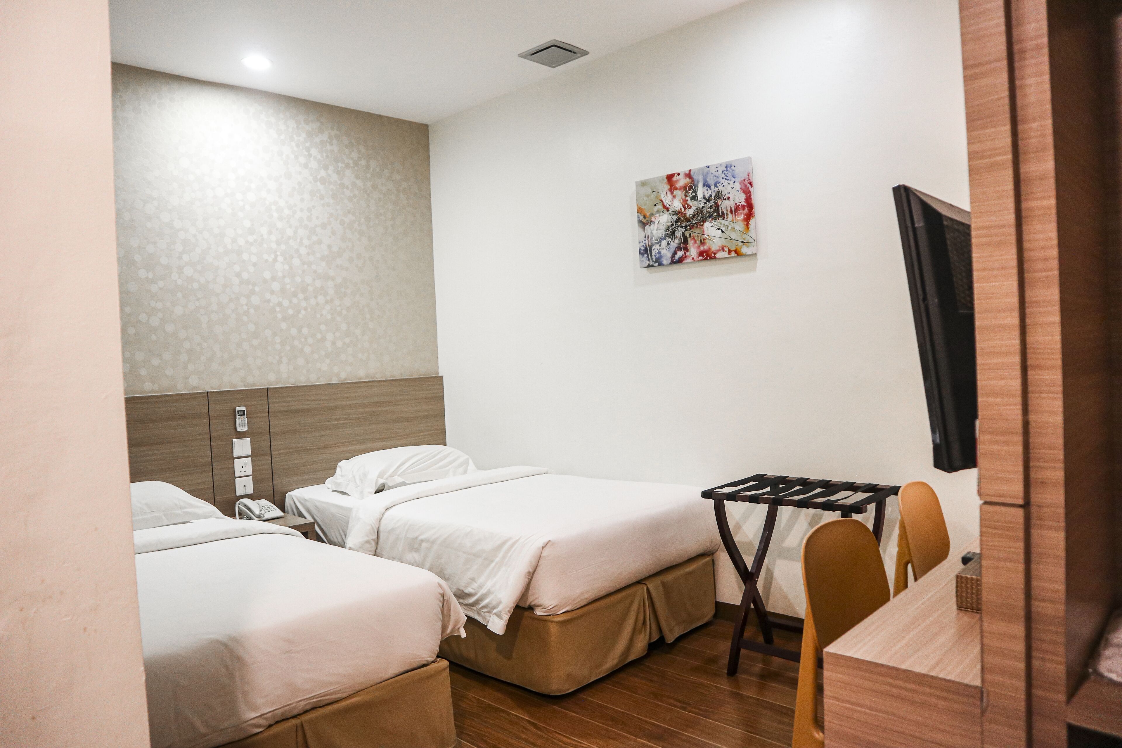 Ein Hotelzimmer mit zwei Betten, einem Schreibtisch und einem Stuhl.
