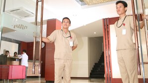 A modern hotel lobby with a glass entrance, a reception desk, and a staircase leading to an upper level. - Hana Hotel (Batam)