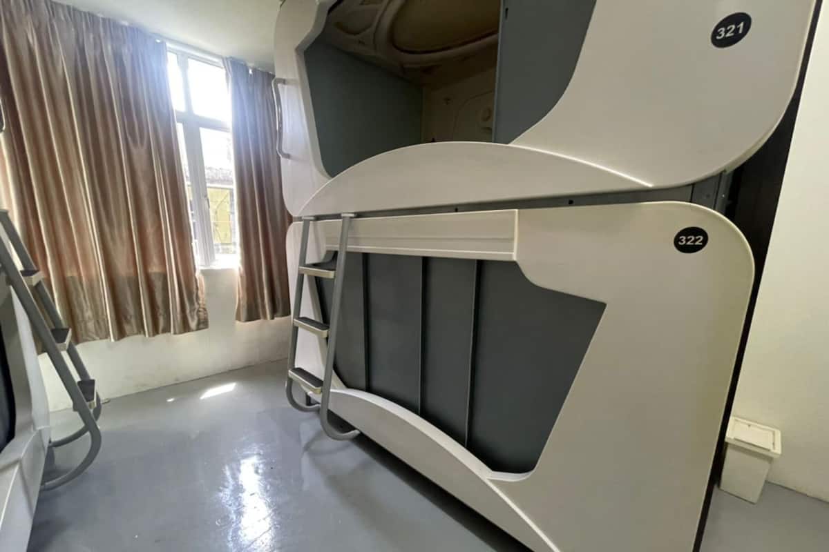 A bunk bed with a ladder, a window with curtains, and a clean floor.