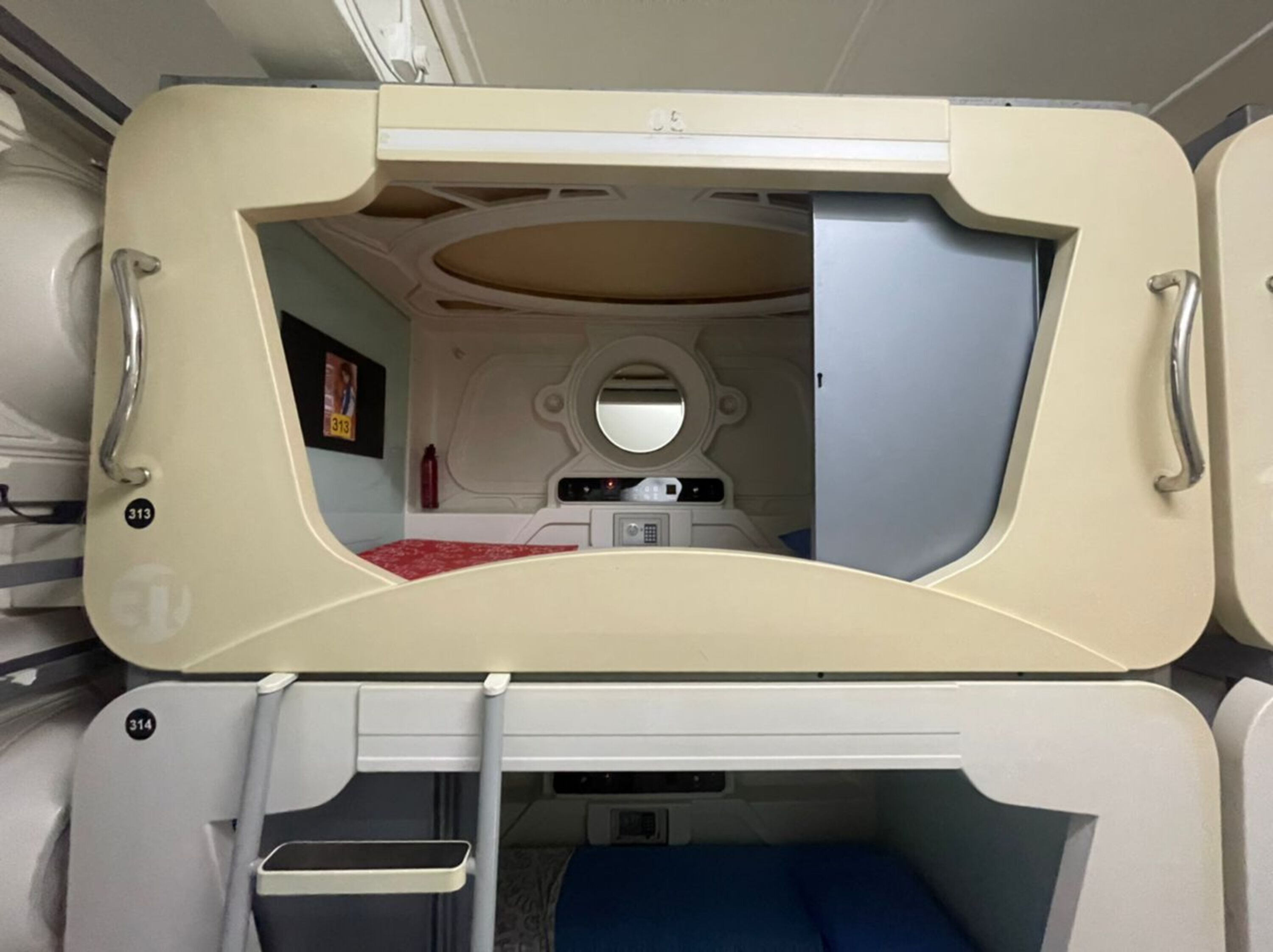 A compact, well-lit interior with a bunk bed, a small table, and a mirror.