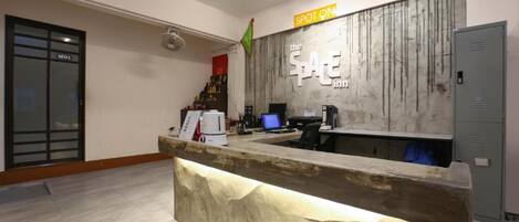 A reception desk with a marble top and a wooden accent, a sign reading "the SPACE inn," and a flag on the wall.