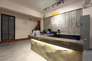 Una recepción con encimera de mármol y detalles de madera, un cartel que dice "the SPACE inn" y una bandera en la pared.