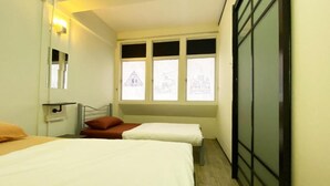 A bedroom with two beds, a window with a view of a building, and a wardrobe. - Hotel O The Space Inn (Kuala Terengganu)