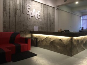 A reception area with a stone wall, a red sofa, and a reception desk. - Hotel O The Space Inn (Kuala Terengganu)