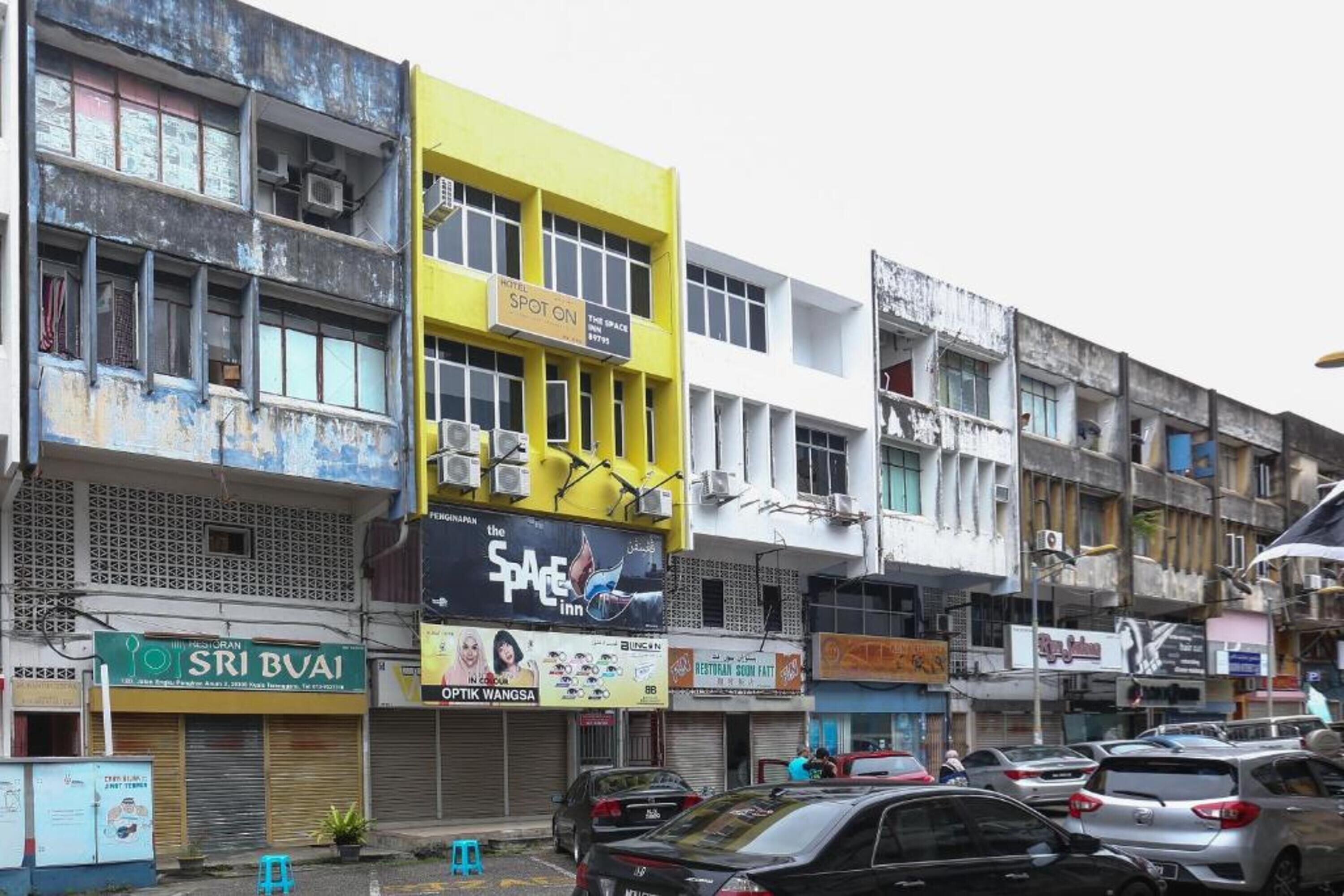 A multi-story building with various shops and a prominent yellow sign for a hotel named "SPOT ON".
