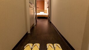A hotel hallway with a bed at the end, a wooden floor, and flip-flops on the floor. - The Pagoda Experience (Kyoto)