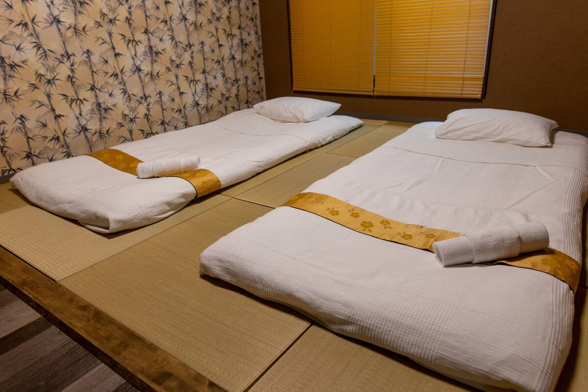 A room with two single beds, each with a white mattress and a yellow decorative strip.