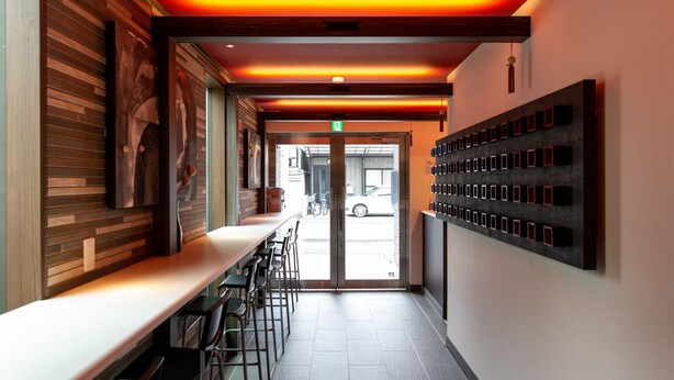 A modern interior with a long counter, bar stools, and a wall-mounted display. - The Pagoda Experience (Kyoto)