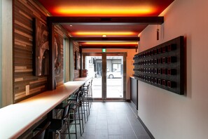 A modern interior with a long counter, bar stools, and a wall-mounted display. - The Pagoda Experience (Kyoto)