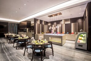 A modern restaurant with a marble floor, wooden tables, and chairs. There is a central island with a water feature and a refrigerated display case.