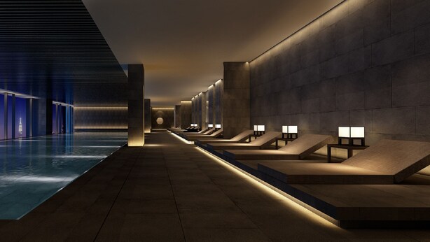 Uma área interna de piscina moderna, com um caminho reto e longo que leva à piscina, ladeado por áreas de estar com mesas e luminárias.