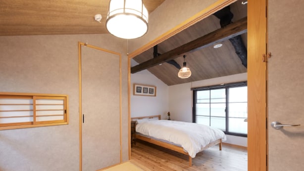 A bedroom with a bed, a wooden ceiling, a window, and a sliding door. - Kyomachiya KANAU (Kyoto)