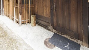 A traditional Japanese building with a wooden exterior, a sliding door, and a lantern. - Kyomachiya KANAU (Kyoto)