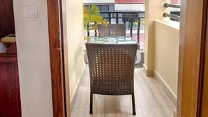 A narrow hallway leading to a balcony with a wicker chair and a glass table. - Dynsey Boutique Hotel (Phnom Penh)