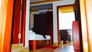 A hotel room with a bed, wooden floor, and a balcony with a chair. - Dynsey Boutique Hotel (Phnom Penh)