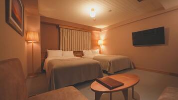 A hotel room with two beds, a television, a lamp, and a small table.