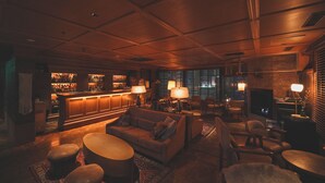 A cozy bar area with a wooden ceiling, a bar counter, and seating including a sofa and chairs. - Unwind Hotel & Bar Sapporo (Sapporo)