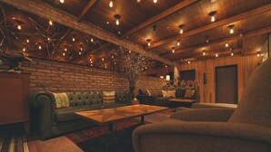 A cozy room with a brick wall, a leather sofa, a wooden coffee table, and a large armchair. - Unwind Hotel & Bar Sapporo (Sapporo)