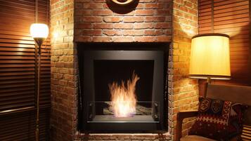 A fireplace with a brick wall, a wooden ceiling, and a patterned floor.