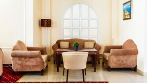 A living room with a sofa set, a dining table, and a chandelier. - Hotel Tengri (Astana)