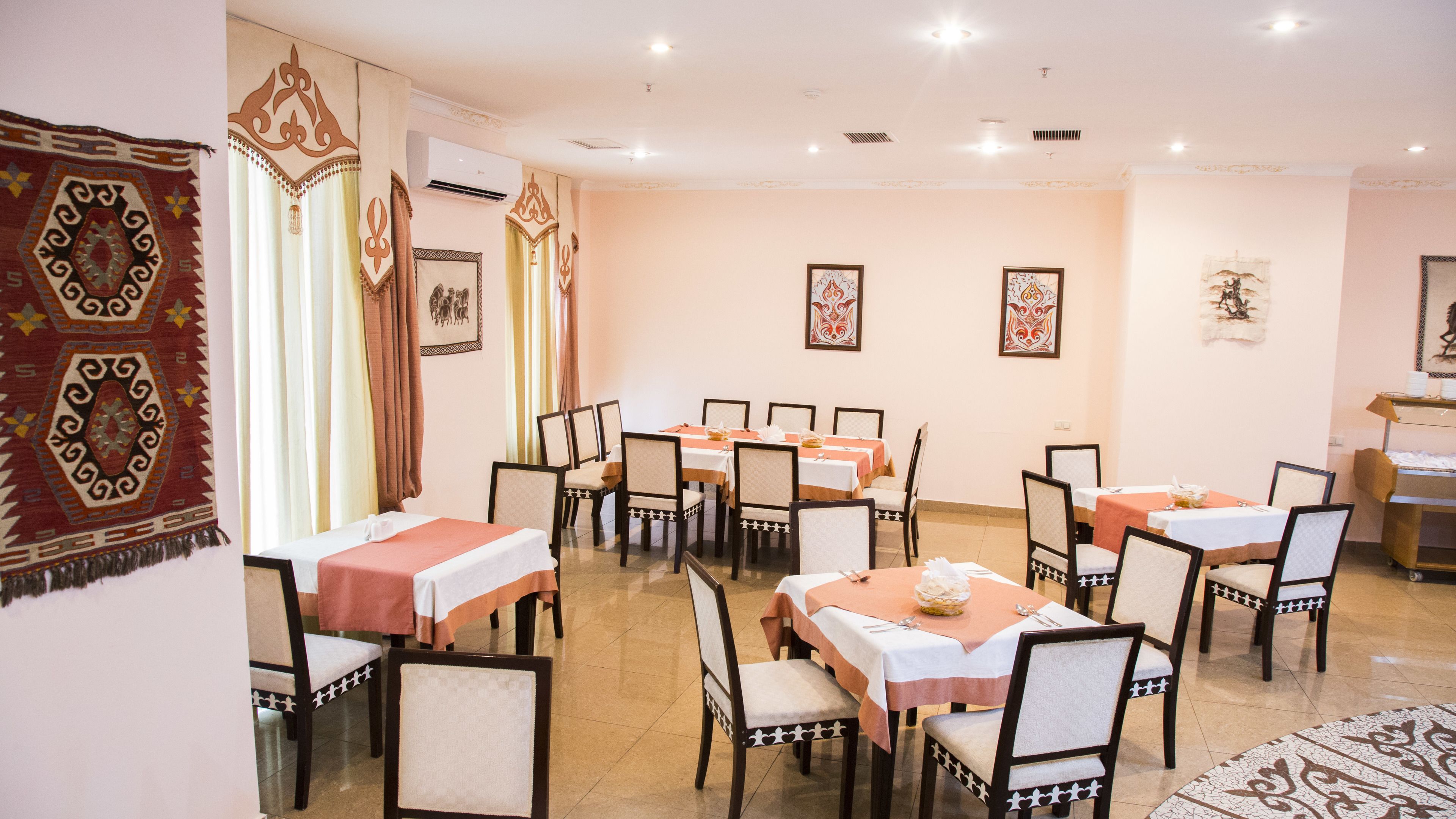 Un comedor con varias mesas y sillas, unidades de aire acondicionado y adornos en la pared.