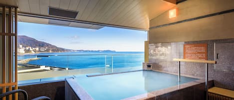 A modern indoor swimming pool with a view of the sea and a cityscape.