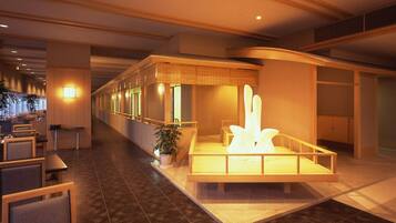 Vestíbulo de hotel con mostrador de recepción, zona de estar y una fuente decorativa.