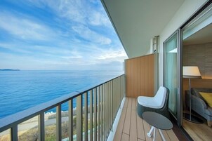 Un balcone con vista sul mare, una sedia, un tavolo e un divano.