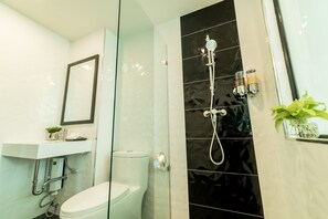 A modern bathroom with a glass shower enclosure, a toilet, and a sink with a mirror above it.