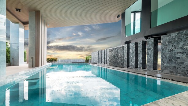 En moderne indendørs swimmingpool med kig til himlen og solnedgang.