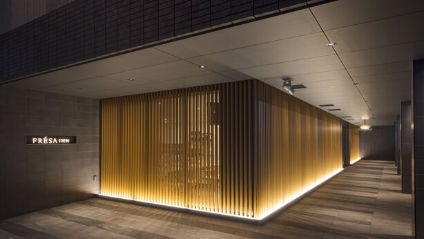 Een moderne hotelentree met een strakke, verlichte receptiebalie en een schone, betegelde vloer.