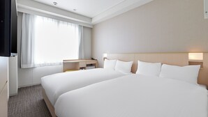 Een hotelkamer met twee bedden, een bureau en een raam met gordijnen.