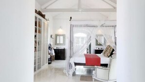 A spacious room with a high ceiling, a bed with a red accent, a wardrobe, and a mirror. - The Sun House (Galle)