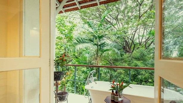 A balcony with a bathtub, surrounded by lush greenery. - The Sun House (Galle)