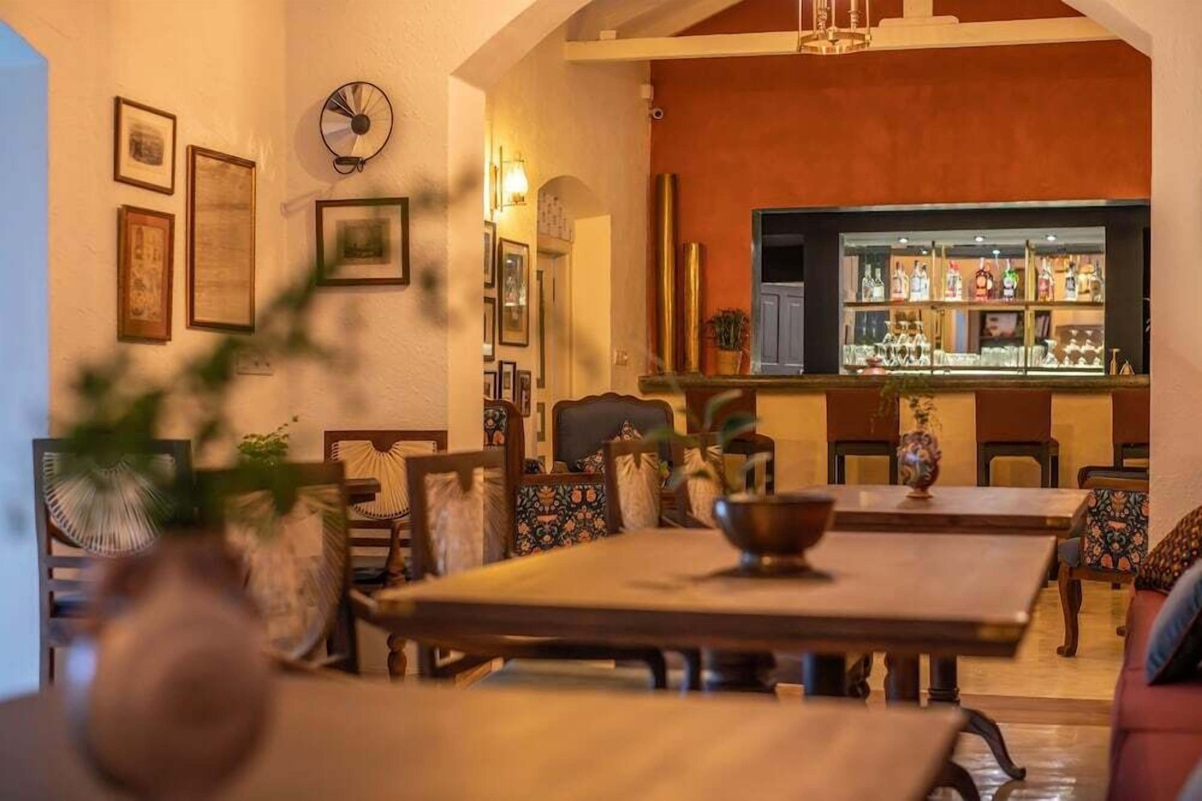 A dining area with a bar in the background, featuring wooden furniture and framed pictures on the walls.