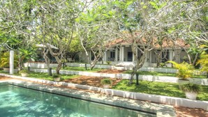 A swimming pool with a tiled deck, surrounded by lush greenery and trees. - The Sun House (Galle)