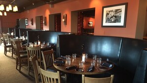 A restaurant with booths and tables, each set with plates, glasses, and cutlery. - Hotel Mezzo (Lima)