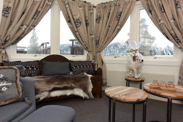 A cozy room with a sofa, a fur throw, a wooden table with glasses, and a decorative dog statue.