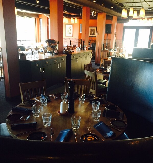 A restaurant with a wooden dining table set for two, surrounded by chairs.