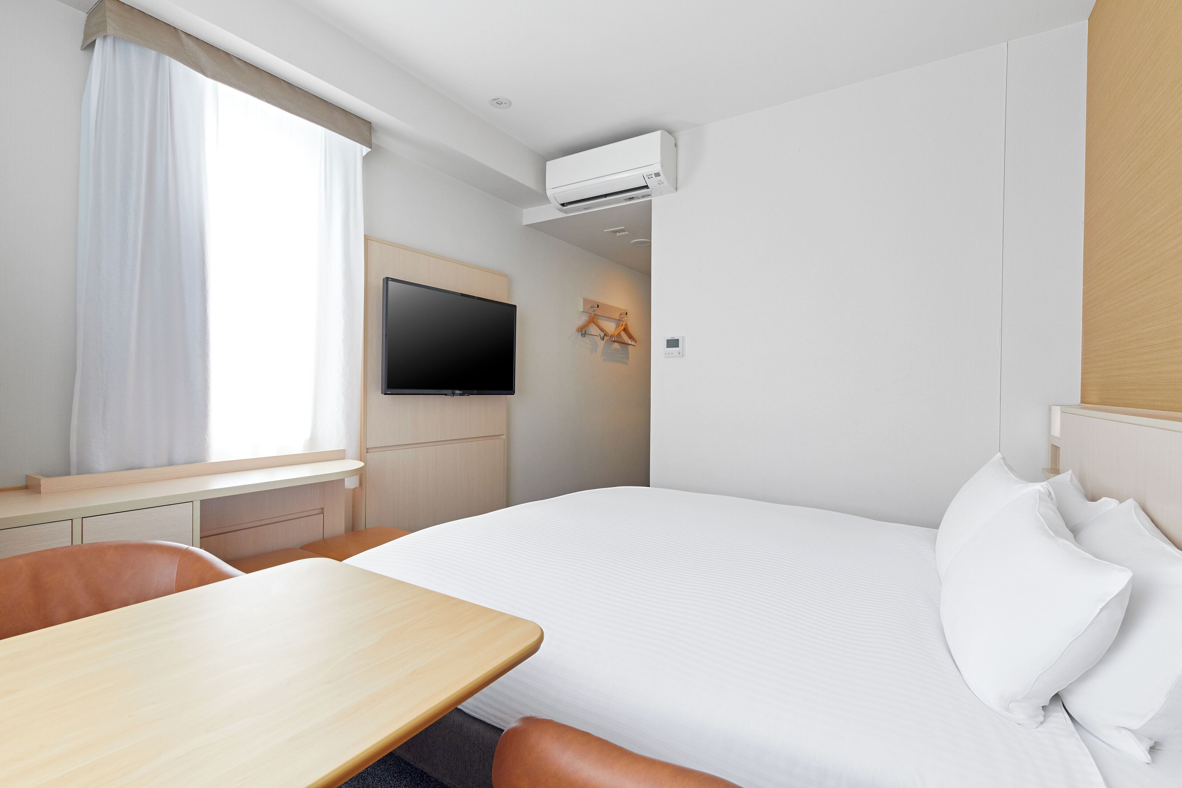 Habitación de hotel con cama, televisor montado en la pared, escritorio y una silla.