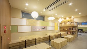Un interior moderno con mesas y bancos de madera, una estantería llena de libros y decoración mural.