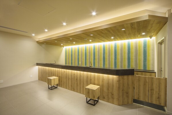 A modern reception area with a wooden counter, two stools, and a striped curtain.
